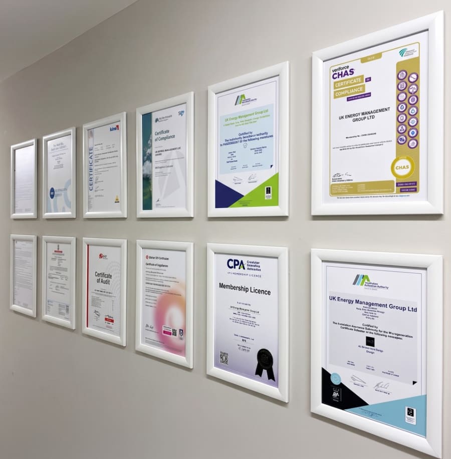 Wall of framed UKEM compliance certificates including CHAS, CPA, and IAA accreditations