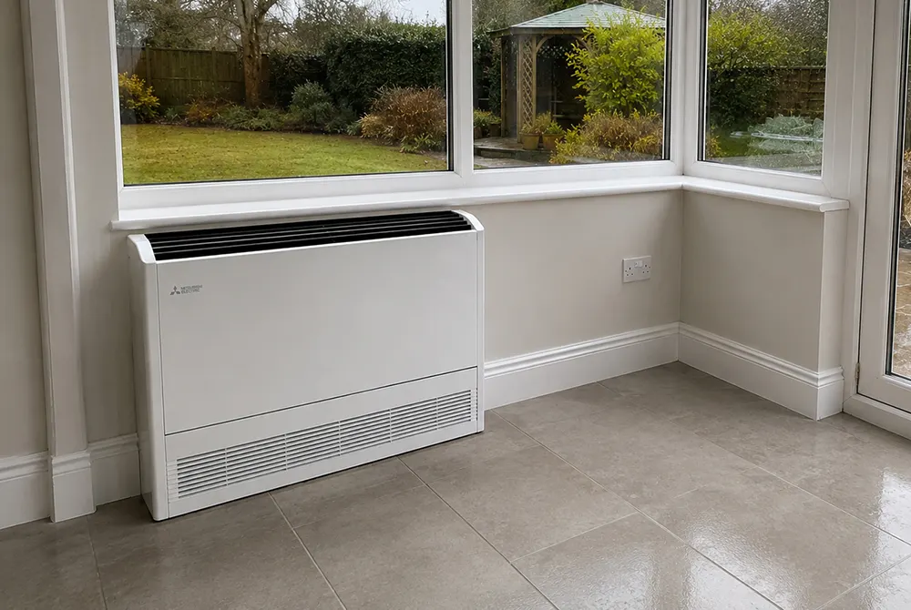 Floor-mounted electric heating unit under a window overlooking a garden