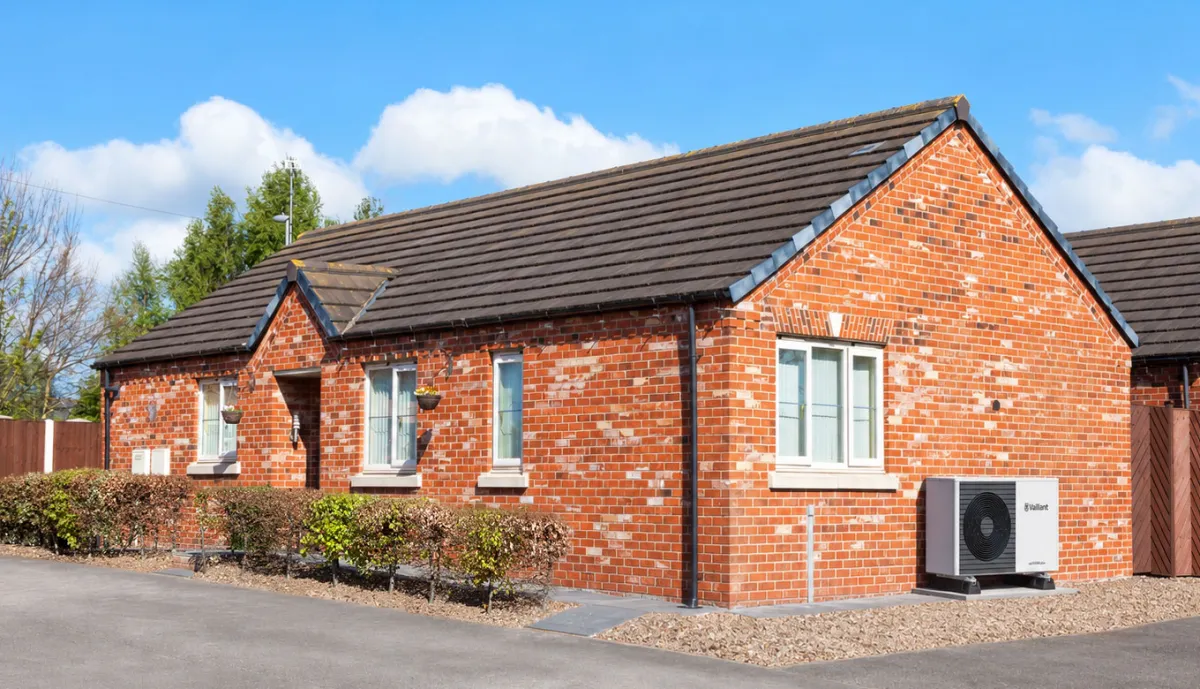 Vaillant air source heat pump installed on a gravel base beside a red-brick UK bungalow