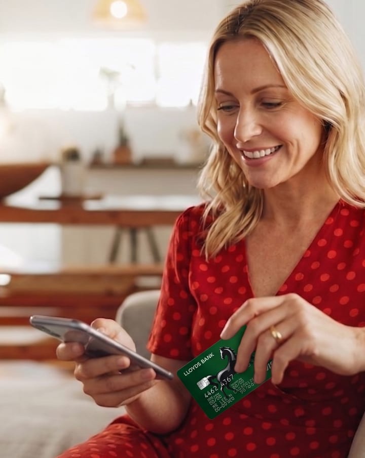 Homeowner at home using a smartphone with a debit card, reviewing payment options