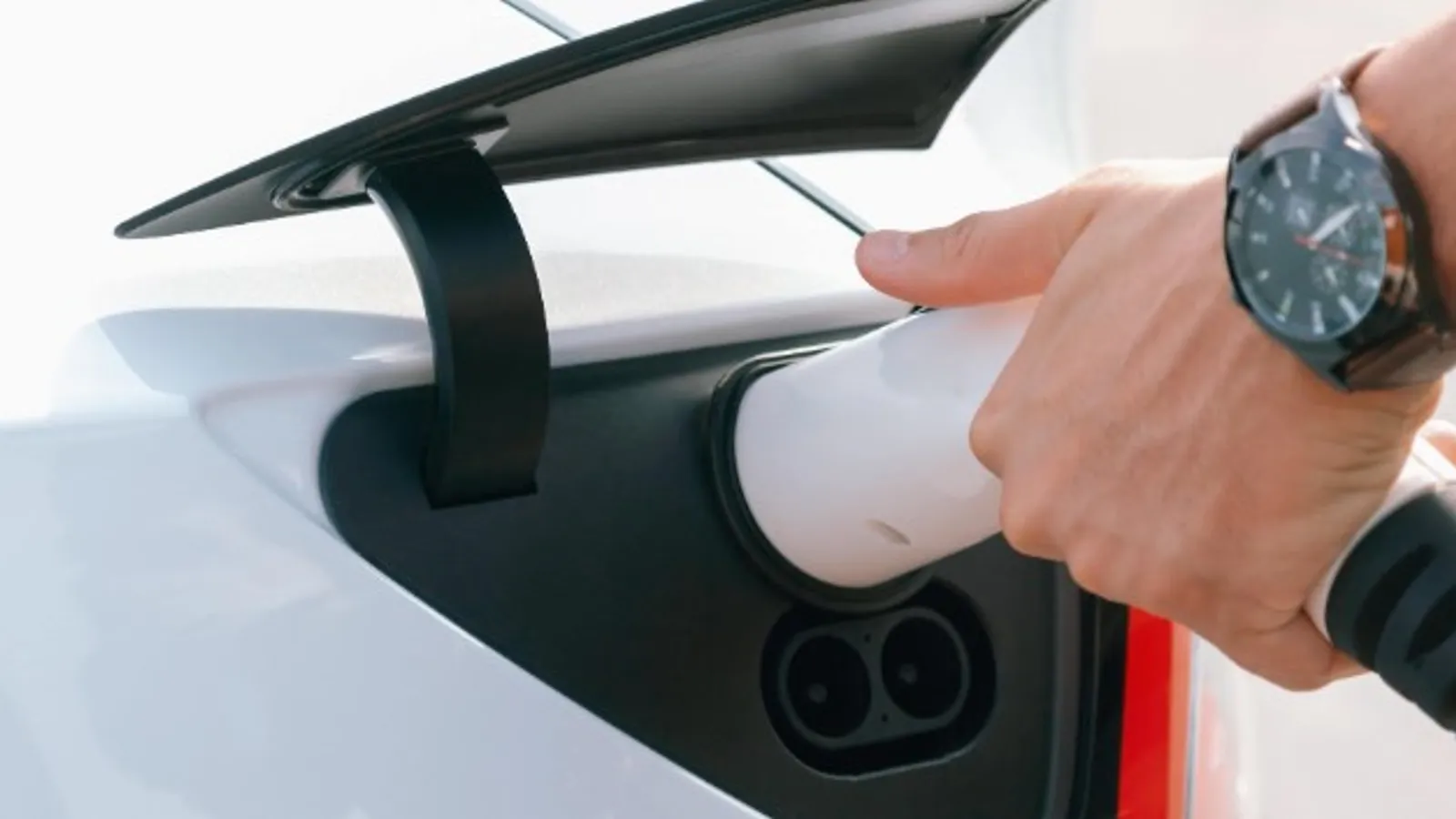 Close-up of an EV charging plug being inserted into an electric car, set against the UK's growing 120,000-strong charger network