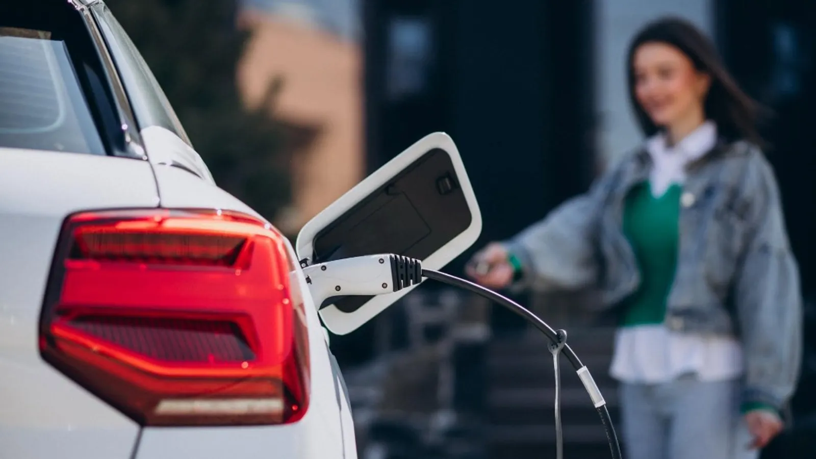 Driver charging an electric car at home using a UK-installed wall-mounted EV charger