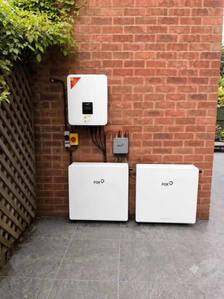 Fox ESS hybrid inverter and twin home battery units on a UK brick wall, typical of record domestic battery uptake