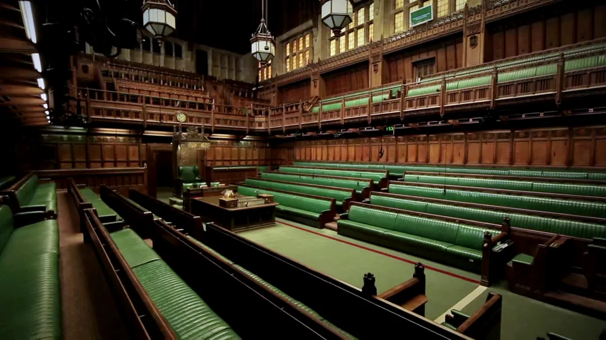 The empty chamber of the House of Commons, with rows of green benches either side of the Despatch Box