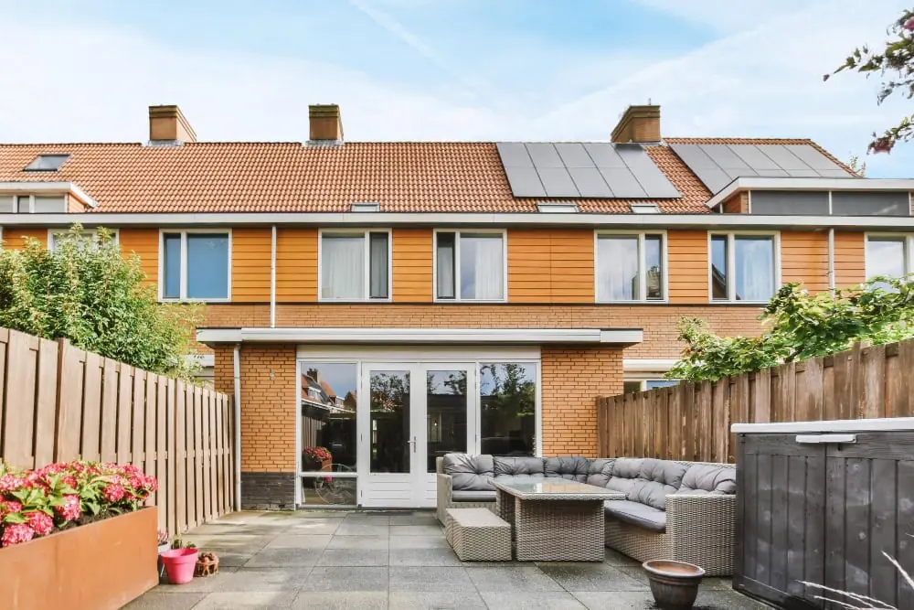 UK terraced house with solar panels on the roof and a paved rear garden patio below the array