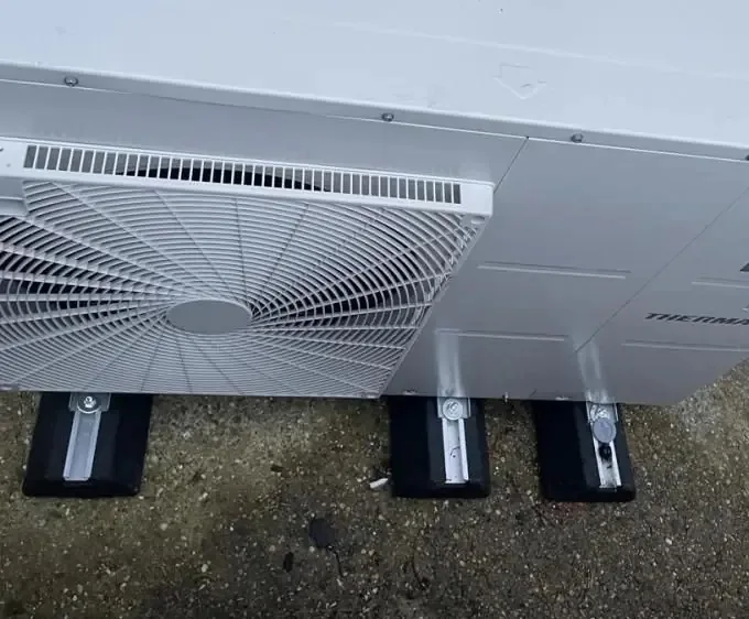 Close-up of an outdoor heat pump unit standing on anti-vibration feet