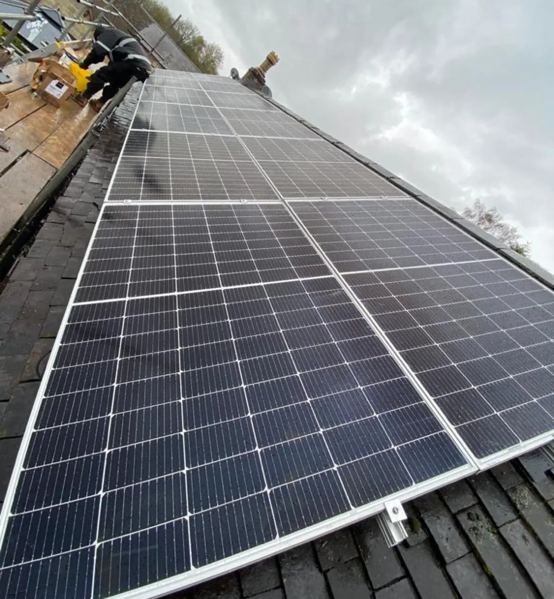 Installer working from scaffolding at the top of a newly fitted row of solar panels