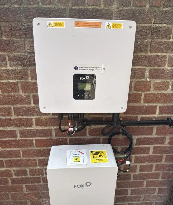Fox ESS inverter on a brick wall, with a Fox ESS home battery fitted below it