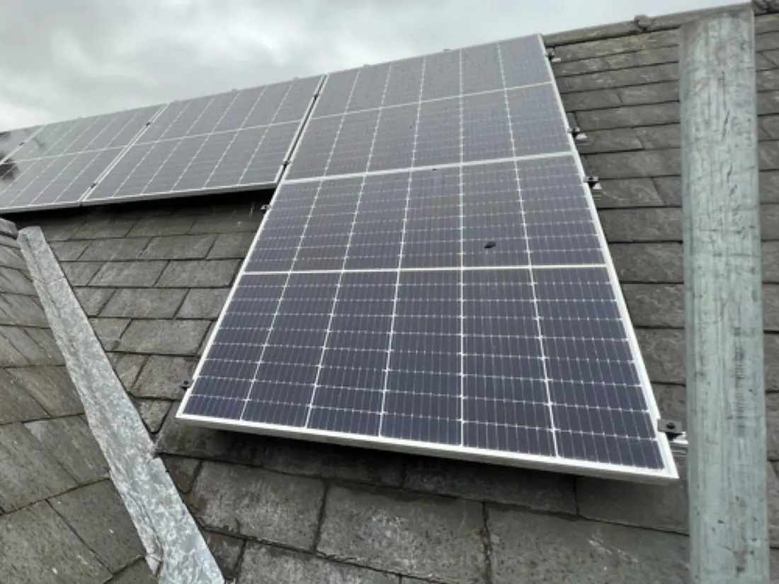 Solar panels on a slate roof, with a scaffold pole beside them