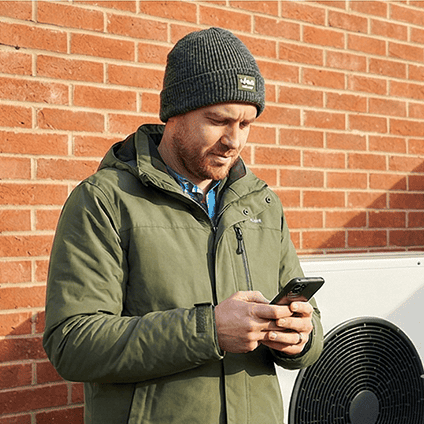 Homeowner checking their heat pump monitoring app on a smartphone outside