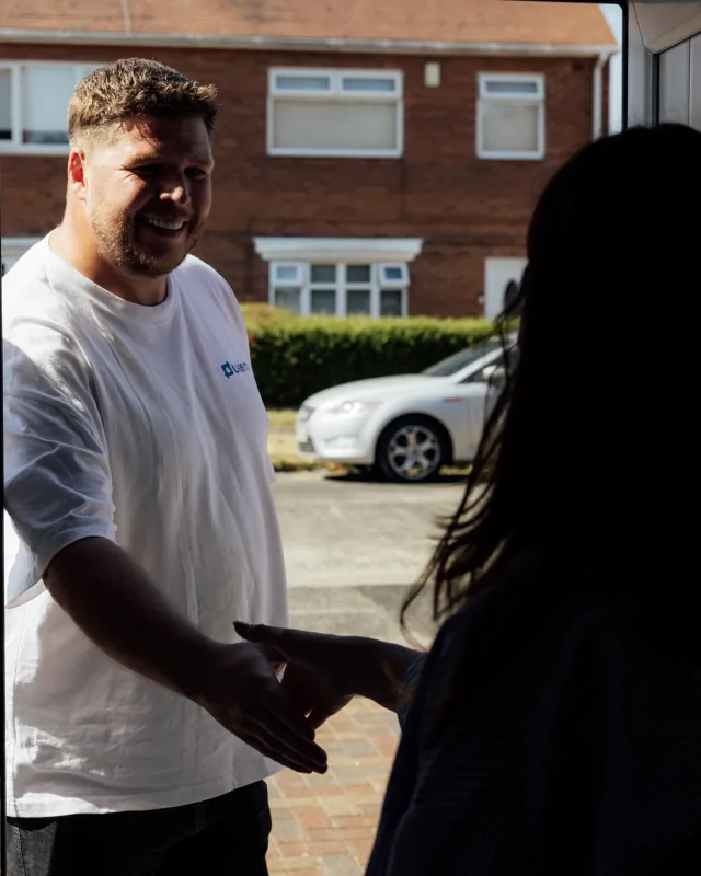 Smiling UKEM installer shaking hands with the customer at her front door