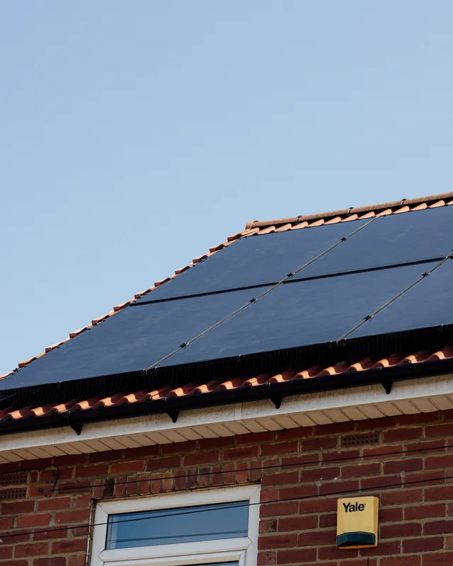 Solar panels on a tiled roof against a clear blue sky