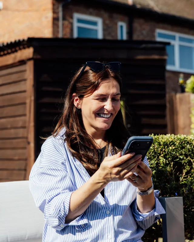 Sophie smiling as she checks her phone in the garden