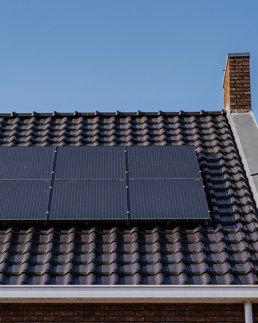 Black solar panels on a UK home tiled roof under a clear blue sky
